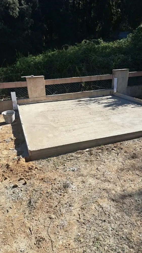 Dalle en béton terminée au pied d’une clôture en bois