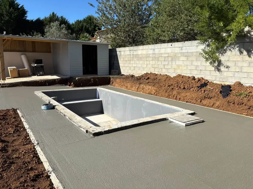 Bassin de piscine enduit et plage en béton devant un abri de jardin