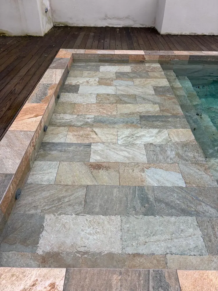 Bassin de piscine revêtu de pierre naturelle, terrasse en bois