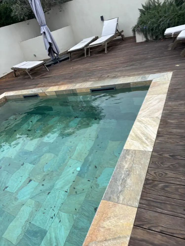 Piscine revêtue de pierre avec terrasse en bois et transats