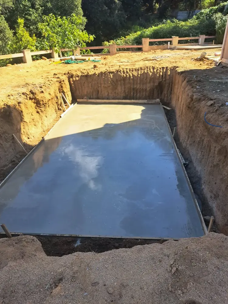 Fond de piscine en béton fraîchement coulé dans la fosse