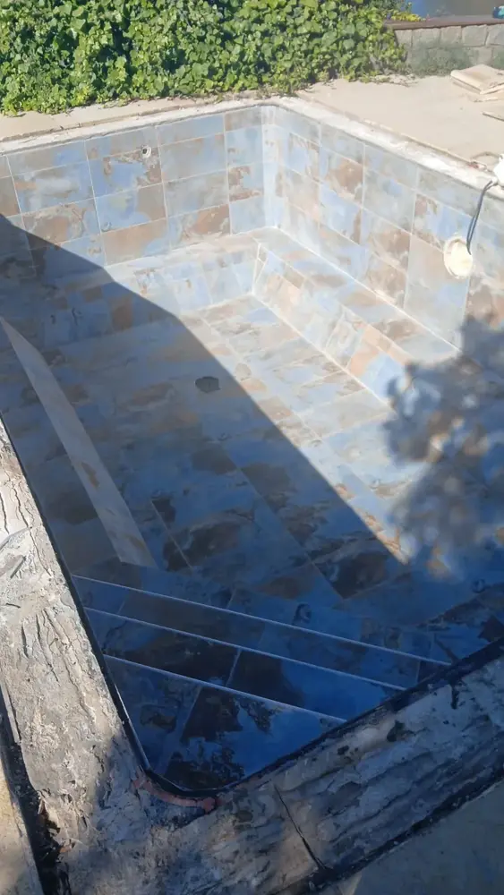 Revêtement en pierre en cours de pose dans un bassin de piscine